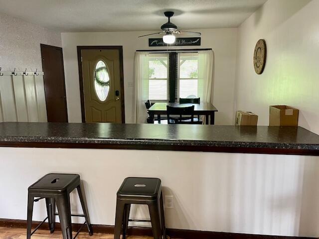 10363 Bremen Rd, Logan, OH 43138 - kitchen with a ceiling fan, a breakfast bar area, wood finished floors, and dark countertops