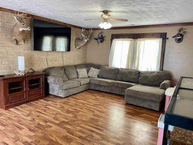 10363 Bremen Rd, Logan, OH 43138 - living room with a ceiling fan, a textured ceiling, light wood-style flooring, and brick wall