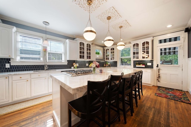 2465 E Broad St, Bexley, OH 43209 - kitchen with ornamental molding, a kitchen island, wood finished floors, stainless steel gas stovetop, and a breakfast bar area