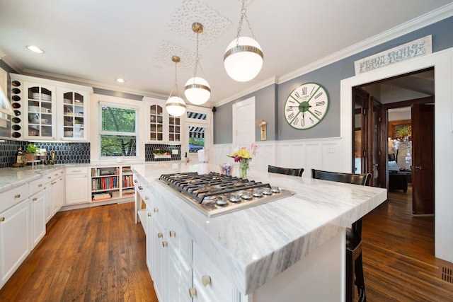 2465 E Broad St, Bexley, OH 43209 - kitchen with ornamental molding, stainless steel gas stovetop, glass insert cabinets, a breakfast bar, and white cabinetry