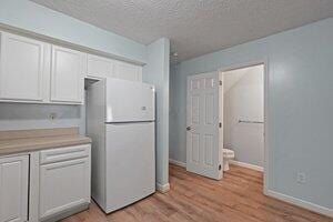 5177 Novelty Ave Unit 72C, Canal Winchester, OH 43110 - kitchen featuring freestanding refrigerator, white cabinetry, light wood-style flooring, a textured ceiling, and light countertops
