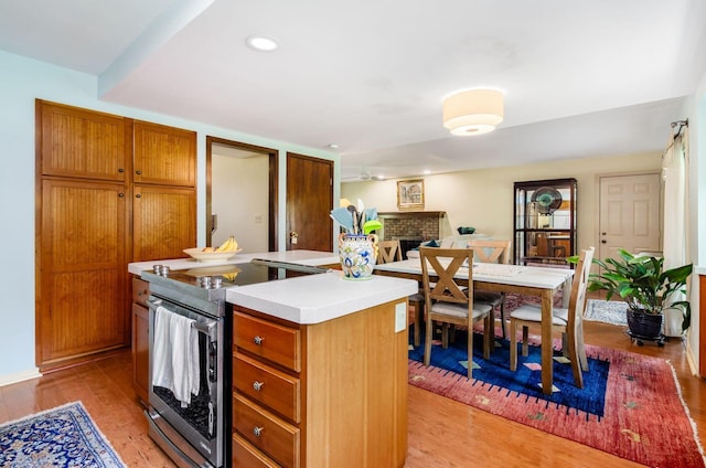 1133 Rockport Ln, Columbus, OH 43235 - kitchen featuring stainless steel electric range, a fireplace, light wood-type flooring, light countertops, and a center island