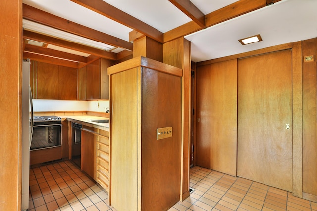230 E S St, Worthington, OH 43085 - kitchen featuring light tile patterned floors, gas stove, freestanding refrigerator, black dishwasher, and elevator