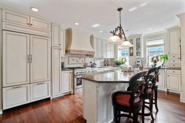 161 Jackson St, Columbus, OH 43206 - kitchen featuring custom exhaust hood, high end range, dark wood-style floors, backsplash, and a kitchen island