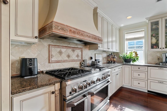 161 Jackson St, Columbus, OH 43206 - kitchen with double oven range, glass insert cabinets, dark stone countertops, dark wood finished floors, and custom range hood