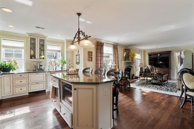 161 Jackson St, Columbus, OH 43206 - kitchen with cream cabinetry, open floor plan, a kitchen bar, crown molding, and recessed lighting