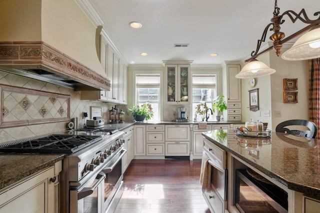 161 Jackson St, Columbus, OH 43206 - kitchen featuring double oven range, custom exhaust hood, dark wood-style floors, dark stone countertops, and cream cabinets