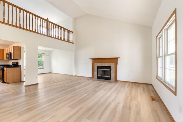 113 Olentangy Meadows Dr, Lewis Center, OH 43035 - unfurnished living room with light wood-style flooring, a chandelier, a tiled fireplace, and high vaulted ceiling