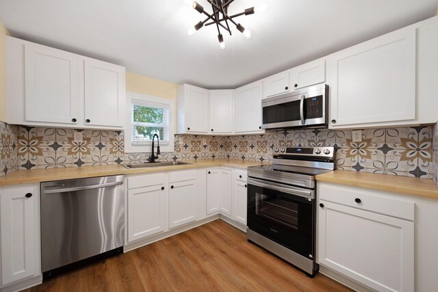 11 E Main St, Sparta, OH 43350 - kitchen with stainless steel appliances, light wood-type flooring, white cabinets, and butcher block counters