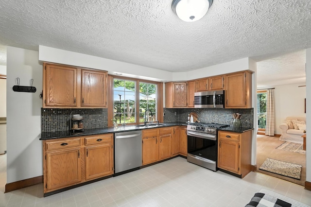1482 Buckpoint Ln, Worthington, OH 43085 - kitchen featuring appliances with stainless steel finishes, dark countertops, brown cabinets, tasteful backsplash, and a textured ceiling