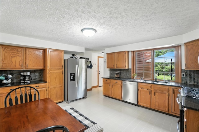 1482 Buckpoint Ln, Worthington, OH 43085 - kitchen with appliances with stainless steel finishes, dark countertops, backsplash, brown cabinets, and a textured ceiling