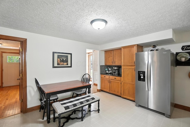 1482 Buckpoint Ln, Worthington, OH 43085 - kitchen featuring stainless steel fridge with ice dispenser, brown cabinetry, a textured ceiling, and decorative backsplash