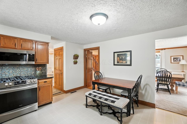 1482 Buckpoint Ln, Worthington, OH 43085 - kitchen featuring stainless steel appliances, dark countertops, decorative backsplash, brown cabinetry, and light floors