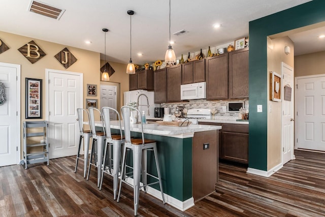 5070 River Bend Dr, South Bloomfield, OH 43103 - kitchen with white appliances, dark wood-type flooring, light countertops, backsplash, and a breakfast bar