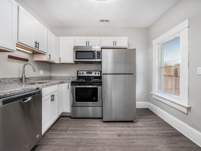 126 E 6th Ave Unit 126, Columbus, OH 43201 - kitchen featuring stainless steel appliances, white cabinets, light stone countertops, and dark wood-type flooring
