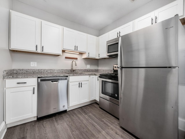 126 E 6th Ave Unit 126, Columbus, OH 43201 - kitchen featuring appliances with stainless steel finishes, dark wood finished floors, light stone counters, and white cabinetry