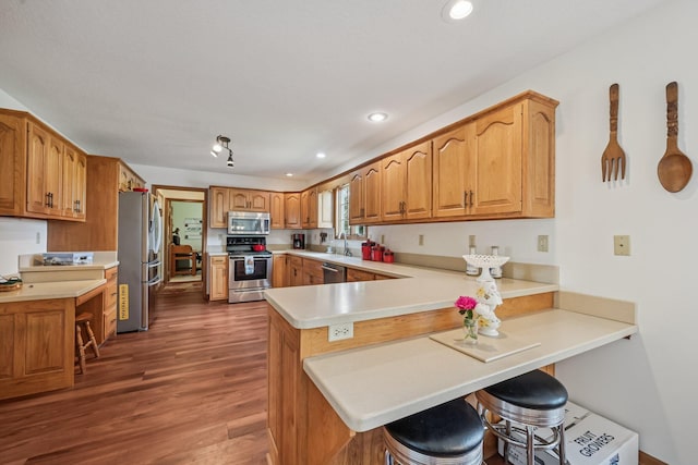 6281 Davis Dr, Newark, OH 43056 - kitchen with stainless steel appliances, a peninsula, dark wood-type flooring, a kitchen bar, and light countertops
