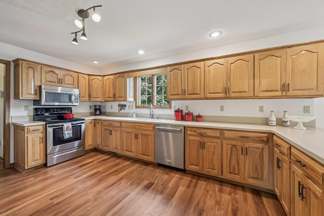 6281 Davis Dr, Newark, OH 43056 - kitchen with stainless steel appliances, light wood-type flooring, light countertops, brown cabinets, and a textured ceiling