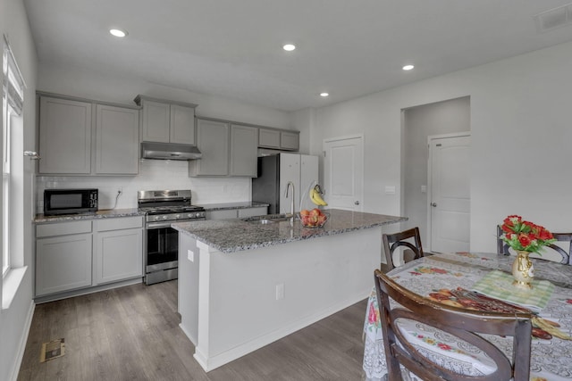 235 Old Bay Dr, Pataskala, OH 43062 - kitchen with gas stove, gray cabinets, under cabinet range hood, freestanding refrigerator, and dark wood-style flooring