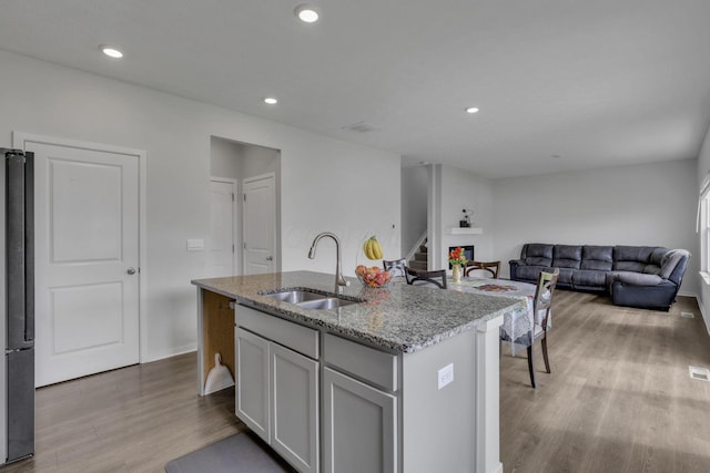 235 Old Bay Dr, Pataskala, OH 43062 - kitchen with wood finished floors, light stone countertops, a kitchen island with sink, freestanding refrigerator, and open floor plan