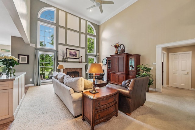6150 Heritage Lakes Dr, Hilliard, OH 43026 - living area with a high ceiling, plenty of natural light, a warm lit fireplace, a ceiling fan, and light colored carpet