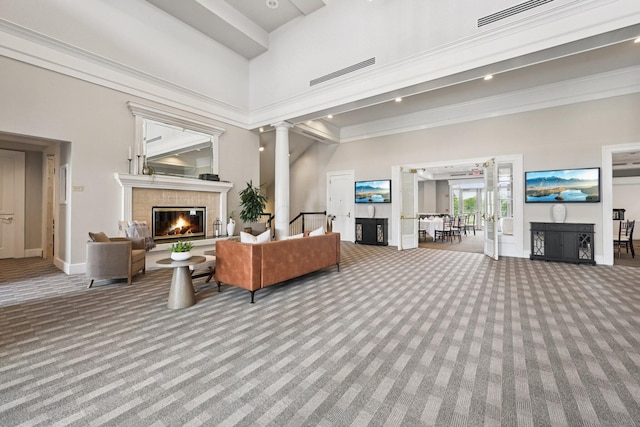 6150 Heritage Lakes Dr, Hilliard, OH 43026 - carpeted living area featuring a tiled fireplace, a towering ceiling, crown molding, and decorative columns