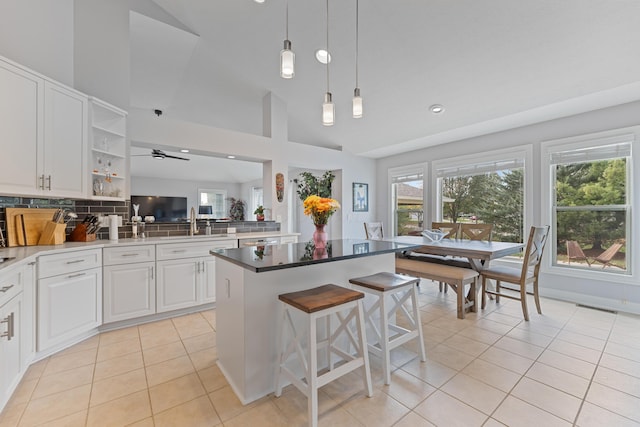 6037 Baronscourt Way, Dublin, OH 43016 - kitchen with light tile patterned floors, a center island, white cabinetry, a breakfast bar area, and decorative backsplash