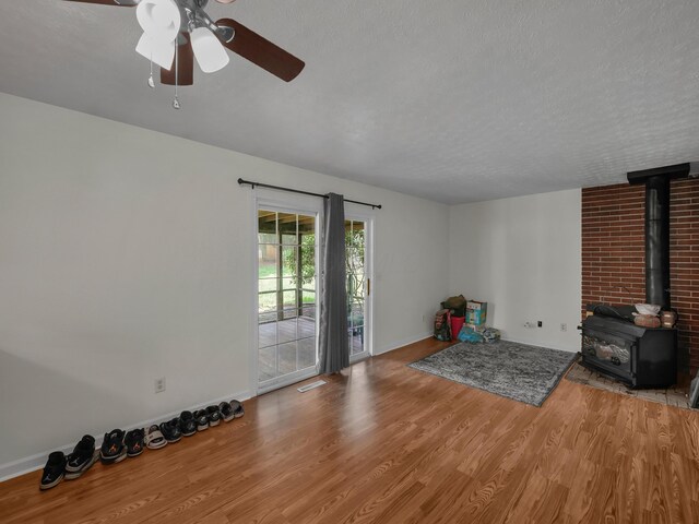 566 Deanna Stroll Rd, Heath, OH 43056 - unfurnished living room featuring wood finished floors, a wood stove, a ceiling fan, and a textured ceiling