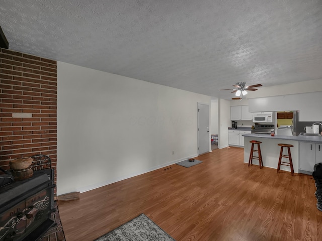 566 Deanna Stroll Rd, Heath, OH 43056 - living room with a textured ceiling, a wood stove, wood finished floors, and a ceiling fan