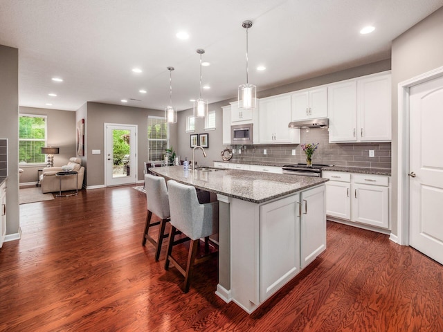 8105 Jitterbug Ln, Pickerington, OH 43147 - kitchen featuring appliances with stainless steel finishes, under cabinet range hood, dark wood finished floors, white cabinetry, and recessed lighting