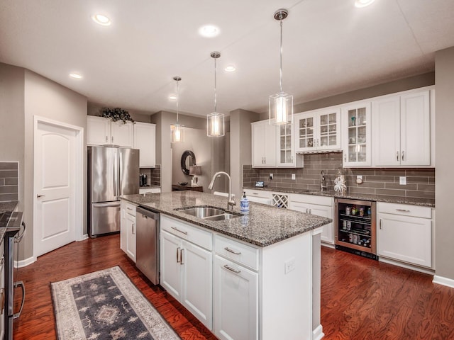 8105 Jitterbug Ln, Pickerington, OH 43147 - kitchen with stainless steel appliances, wine cooler, a kitchen island with sink, glass insert cabinets, and dark wood-style flooring