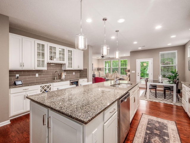8105 Jitterbug Ln, Pickerington, OH 43147 - kitchen featuring stainless steel dishwasher, dark wood finished floors, a kitchen island with sink, white cabinets, and glass insert cabinets