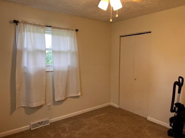67682 Morristown Flushing Rd, Belmont, OH 43718 - unfurnished room featuring a textured ceiling, a ceiling fan, and dark colored carpet