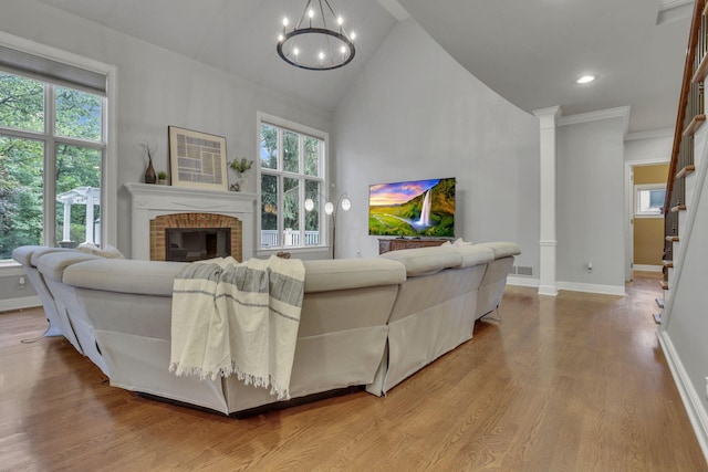 4329 Wyandotte Woods Blvd, Dublin, OH 43016 - living room with a brick fireplace, a chandelier, wood finished floors, high vaulted ceiling, and stairway