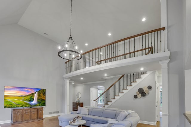 4329 Wyandotte Woods Blvd, Dublin, OH 43016 - living area with high vaulted ceiling, stairs, decorative columns, wood finished floors, and a chandelier