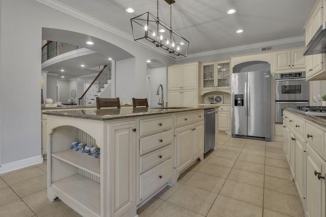 4329 Wyandotte Woods Blvd, Dublin, OH 43016 - kitchen with appliances with stainless steel finishes, cream cabinetry, arched walkways, ornamental molding, and dark stone countertops