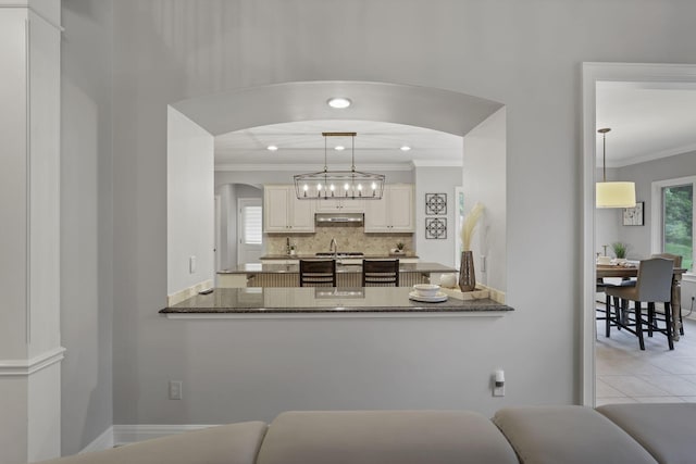 4329 Wyandotte Woods Blvd, Dublin, OH 43016 - kitchen with ornamental molding, arched walkways, backsplash, a peninsula, and under cabinet range hood