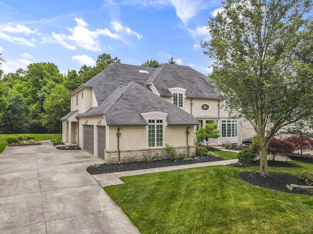 4329 Wyandotte Woods Blvd, Dublin, OH 43016 - french country home featuring stone siding, stucco siding, concrete driveway, a front yard, and an attached garage