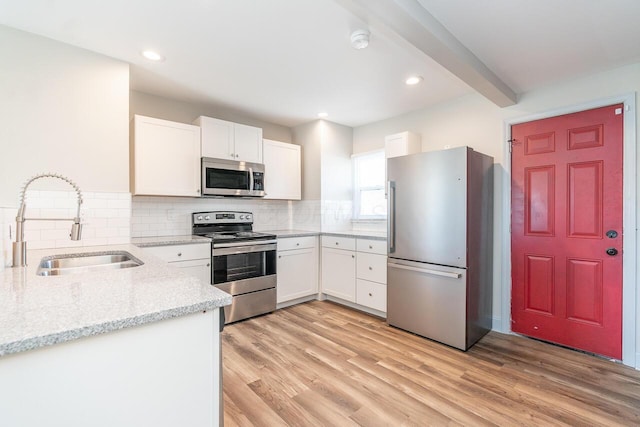 1096 E 22nd Ave Unit 1098, Columbus, OH 43211 - kitchen with appliances with stainless steel finishes, light stone counters, decorative backsplash, light wood-style flooring, and white cabinetry