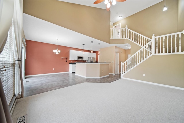 786 Spring Valley Dr, Lewis Center, OH 43035 - unfurnished living room featuring ceiling fan, stairs, a chandelier, carpet floors, and wood finished floors