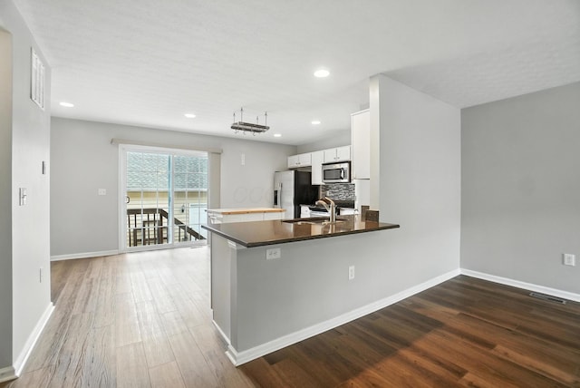 5632 Middle Falls St, Dublin, OH 43016 - kitchen featuring stainless steel appliances, white cabinets, wood finished floors, a peninsula, and tasteful backsplash