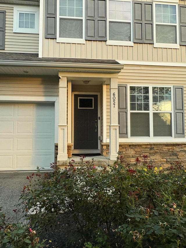 6057 Lakes At Taylor Station Dr, Columbus, OH 43213 - property entrance with a garage, stone siding, and board and batten siding