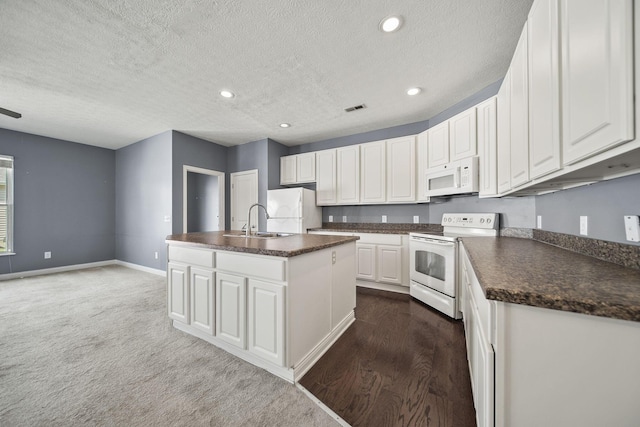 6067 Hayden Farms Rd, Dublin, OH 43016 - kitchen featuring white appliances, dark countertops, white cabinetry, a center island with sink, and a textured ceiling