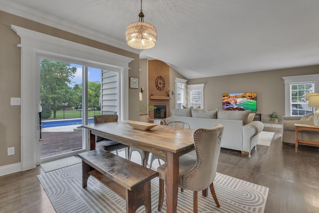 9606 Ireland Ct, Powell, OH 43065 - dining space with a brick fireplace, wood finished floors, a chandelier, and vaulted ceiling
