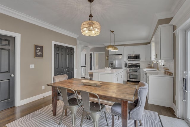 9606 Ireland Ct, Powell, OH 43065 - dining room with ornate columns, crown molding, a chandelier, and dark wood finished floors