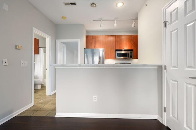 121 E Noble St Unit 3, Columbus, OH 43215 - kitchen featuring appliances with stainless steel finishes, brown cabinets, rail lighting, a peninsula, and light countertops