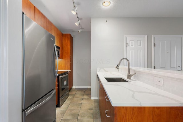 121 E Noble St Unit 3, Columbus, OH 43215 - kitchen featuring stainless steel appliances, brown cabinetry, tasteful backsplash, light stone countertops, and a peninsula