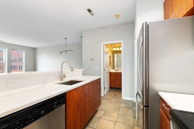 121 E Noble St Unit 3, Columbus, OH 43215 - kitchen with stainless steel appliances, brown cabinets, light stone countertops, pendant lighting, and light tile patterned floors
