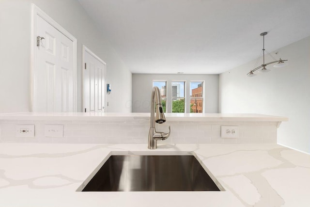 121 E Noble St Unit 3, Columbus, OH 43215 - kitchen featuring decorative backsplash, light stone countertops, and hanging light fixtures