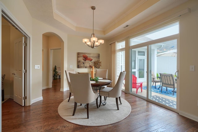 5428 Tathwell Dr, New Albany, OH 43054 - dining space featuring crown molding, arched walkways, dark wood-style floors, a tray ceiling, and a chandelier